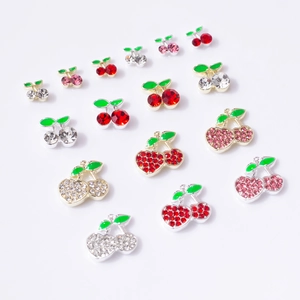 Detailed macro view of 3D cherry nail charms with red crystals and green leaf accents