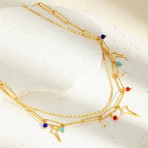 Détail d'un collier doré multicouche avec perles colorées et pendentifs en étoile