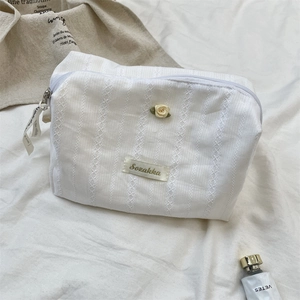 Close-up of white lace embroidered cosmetic bag featuring a yellow fabric rose detail