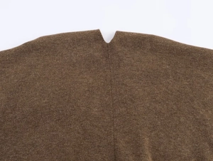 Macro view of dark brown knitted poncho showing soft wool texture and neckline details