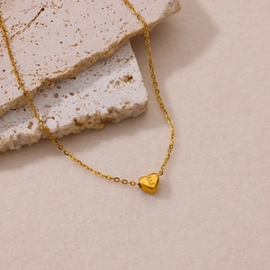 Gold-plated stainless steel heart necklace with letter E on a stone background