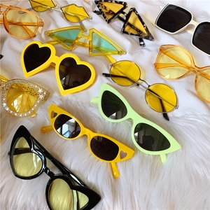 Flat lay of colorful daisy yellow and green square frame sunglasses on white fabric