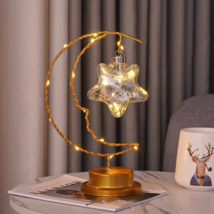 Close-up of golden iron crescent moon and star LED night light on marble tabletop