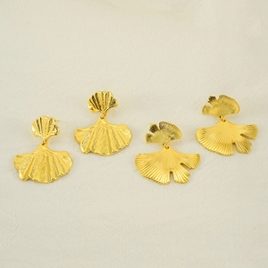 Detailed close-up of golden ginkgo leaf earrings with fine radial metal textures