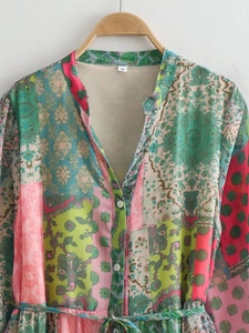 Détail de la robe à col en V avec motif coloré et étiquette taille S sur cintre en bois