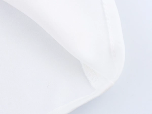 Detailed close-up of white blouse hem showing neat stitching and woven fabric texture