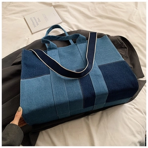 Detail of color-block denim tote bag showing patchwork seams and woven shoulder strap