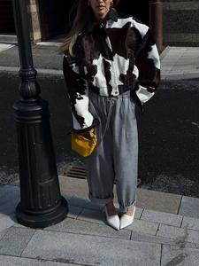 Street style view of a cropped cow print faux fur jacket with elastic hem and wide lapel