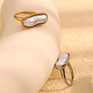 Detail showing gold and silver rings with baroque pearls on a minimalist prop