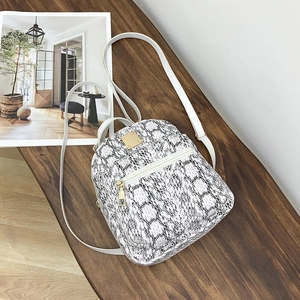 Detail of white snakeskin pattern mini backpack with elegant gold hardware and straps
