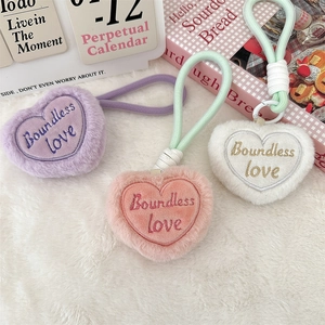 Detailed view of heart-shaped plush keychains with 'Boundless love' embroidery