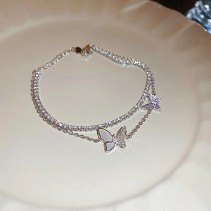 Macro detail of silver butterfly double-layer bracelet with shell inlay on ceramic plate
