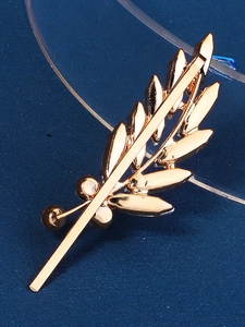 Macro view of a gold leaf bridal hair clip with detailed leaf veins on a blue background