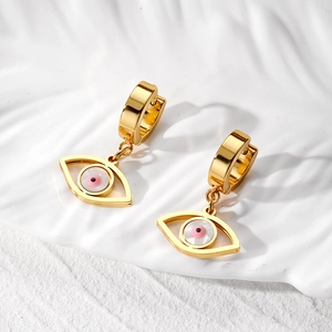 Detailed close-up of gold evil eye drop earrings with pink bead on white wavy background