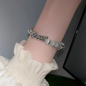 Detail eines Perlenarmbands aus Katzenauge mit Herzanhänger an einer Silberkette