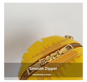 Detailed macro view of smooth golden metal zippers and stitching on yellow round bag