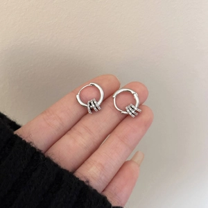 Silver 18k gold plated earrings with zircon hoops being held against beige background