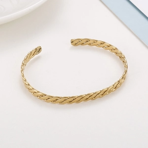 Gros plan d'un bracelet ouvert en métal torsadé doré avec motif de tissage brillant