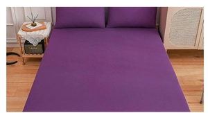 Detail view of deep purple bed linen set with fitted sheet and pillowcases in home setting