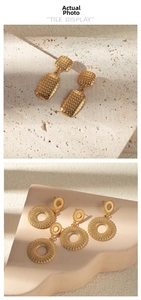 Close-up of gold hollow earrings on stone pedestals featuring grid and sunburst textures