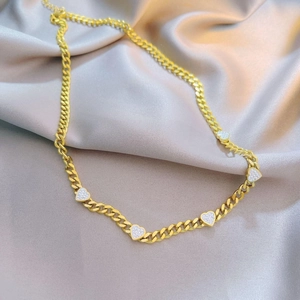 Golden heart cuban chain necklace with micro-paved crystals on champagne silk background