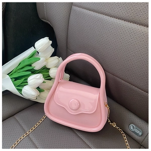 Pink mini jelly bag with gold chain strap on grey leather car seat with tulips