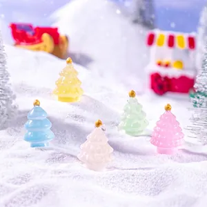 Miniature luminous Christmas trees in pastel colors set on artificial snow decor