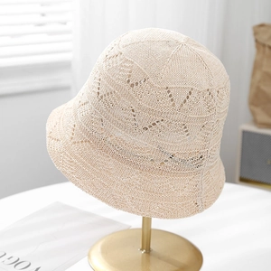 Detailed close-up of beige knitted bucket hat featuring intricate crochet texture on stand