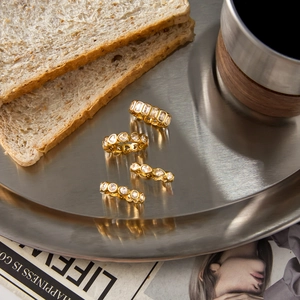 Macro detail of four gold stainless steel rings with sparkling cubic zirconia on a tray