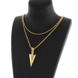 Detail of gold double-layer chain necklace featuring an arrow pendant on a black bust