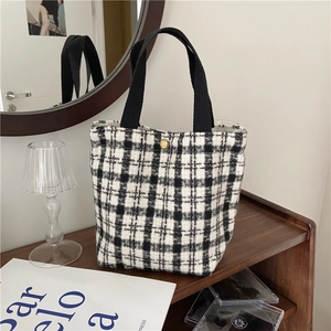 Detail of checkered tote bag with golden clasp on a rustic wooden shelf setting