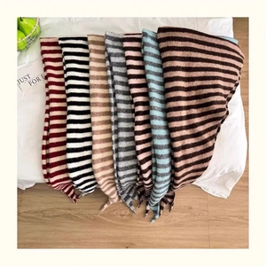 Flat lay of multiple striped wool blend knit scarves in various colors on a bed