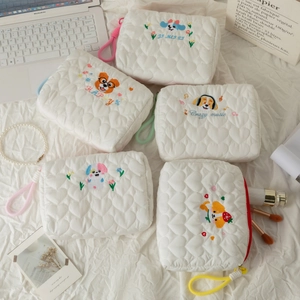 Detailed collection of white quilted cosmetic bags with cute puppy embroidery on a soft fabric