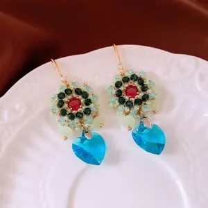 Orecchini a cuore vintage con cristallo celeste e perline su un piatto di ceramica