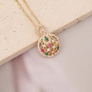 Close-up of golden circular pendant with hollow design and multi-colored zircons on silk