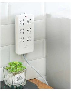 Wall-mounted power strip with six outlets and red switch on a white tile wall