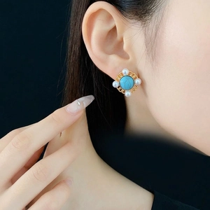 Vintage gold earrings with turquoise stone and pearls shown on an Asian model