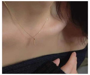 Close-up of minimalist gold-plated bar pendant necklace with small diamonds on model's neck