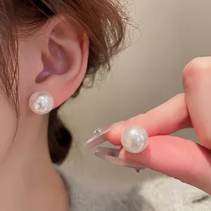Elegant white pearl stud earrings with a glossy finish and minimalist silver pins