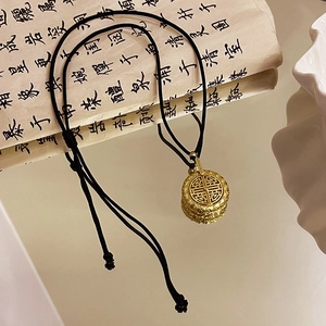 Macro shot of gold filigree necklace pendant on vintage calligraphy paper background