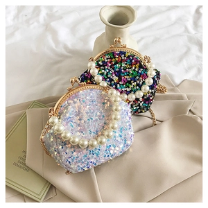 Detail of sequin shell purses with metal clasp and pearl handle on fabric background
