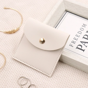 Detail of cream microfiber jewelry pouch with textured finish and gold button closure