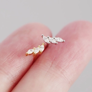 Macro shot of silver and gold marquise zircon stud earrings held between fingers