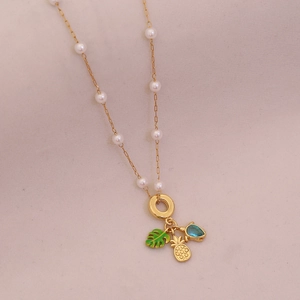Gold necklace featuring white pearls, green leaf, pineapple, and blue teardrop gem pendants