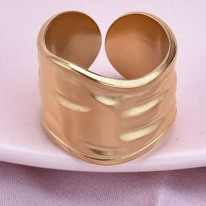 Macro shot of gold-plated wide band ring with irregular hammered texture on silk