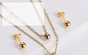 Close-up of minimalist gold-plated jewelry set with spherical stud earrings and pendant