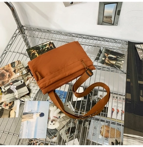 Detail view of water-resistant orange nylon crossbody bag with adjustable strap