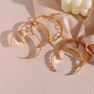Detailed view of gold twisted braid open bracelets on pink silk and bubble candle