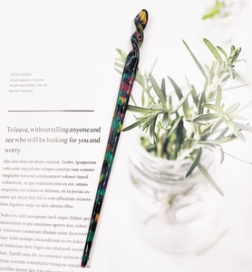 Close-up of a twisted acetate hair pin with colorful marble patterns on art magazine