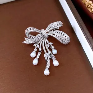 Sparkling zircon bow brooch with elegant pearl tassels on a dark textured display